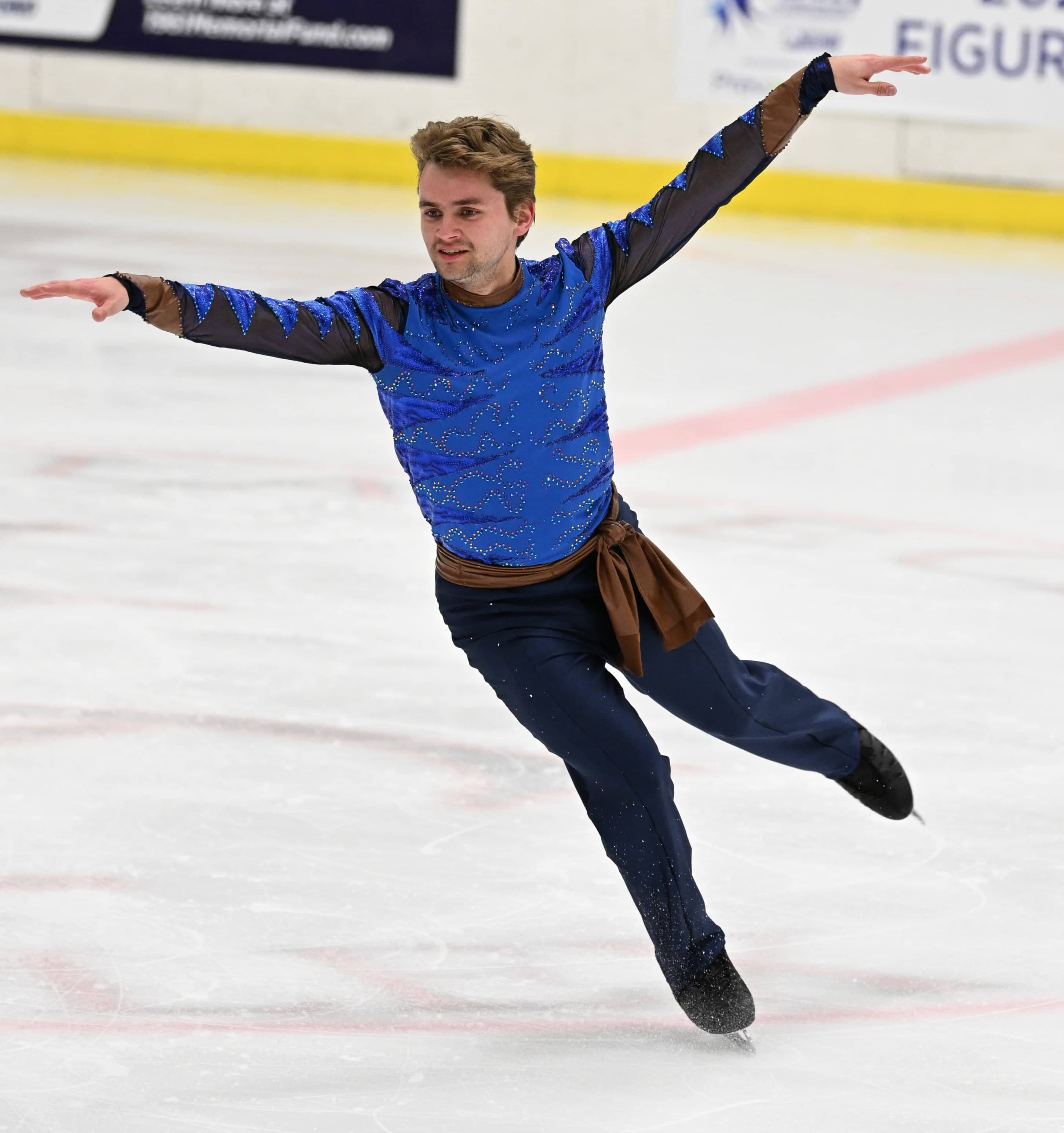 Sasha Dresback skates with his arm extended wearing a dark blue top